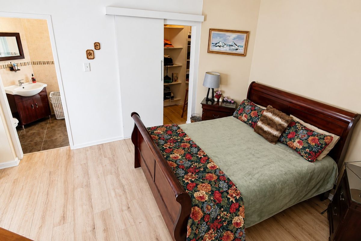 Spacious bedroom featuring light laminate flooring, a convenient sliding door leading to built-in storage, and an adjoining en-suite bathroom.