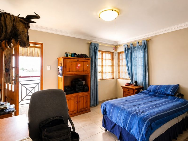 A bedroom featuring tiled flooring, decorative ceiling cornices, and direct access to an outdoor balcony area through a wooden door.