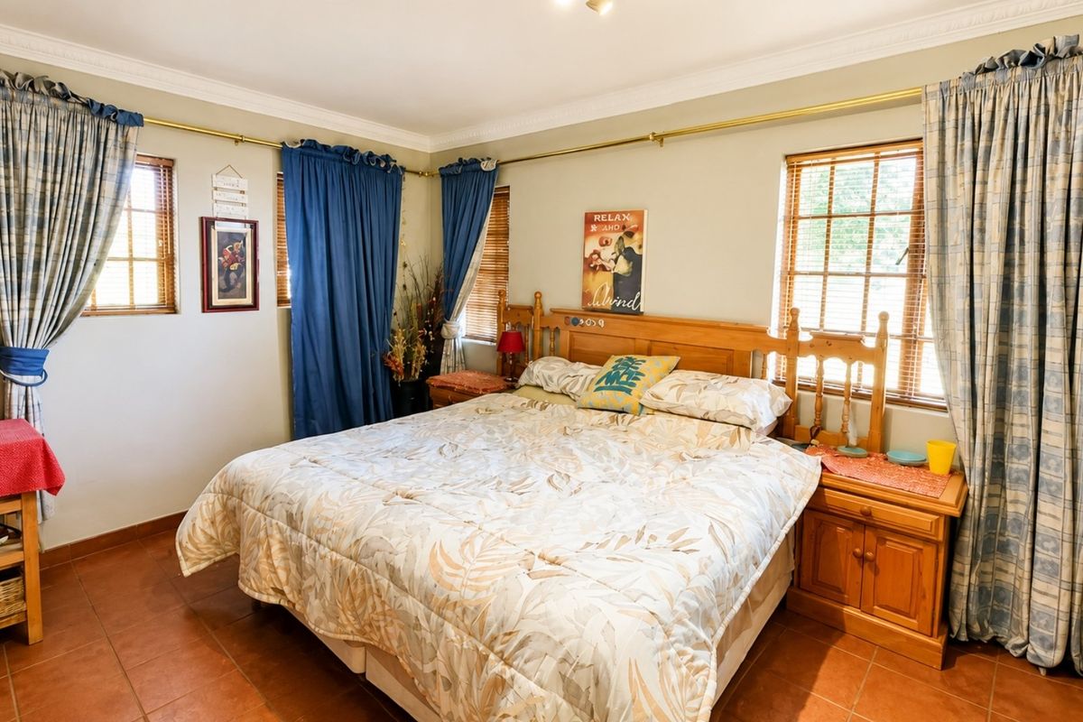 A spacious bedroom featuring tiled flooring, crown molding, and multiple windows with curtain rods, offering a comfortable and functional living space.