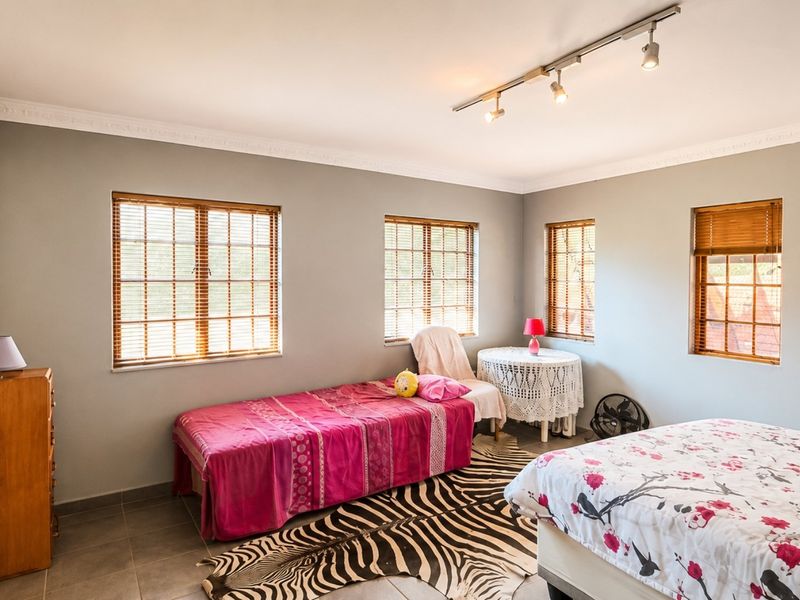 Spacious bedroom featuring tiled flooring, built-in cupboards, and modern track lighting, offering a neutral canvas for personalization.