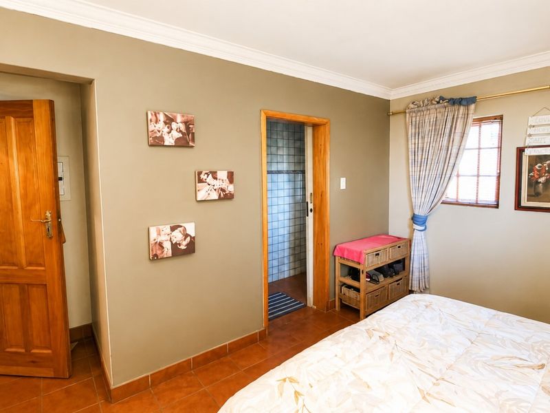 A bedroom featuring tiled flooring, neutral wall tones, and an adjoining bathroom access point with timber door frames.