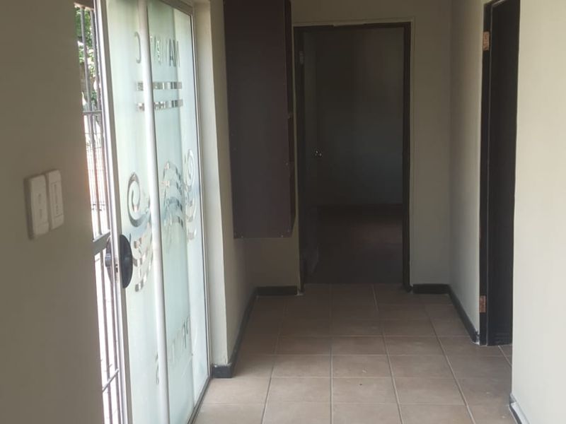 A functional hallway featuring tiled flooring, a sliding glass door providing natural light, and a built-in wall cabinet for storage.