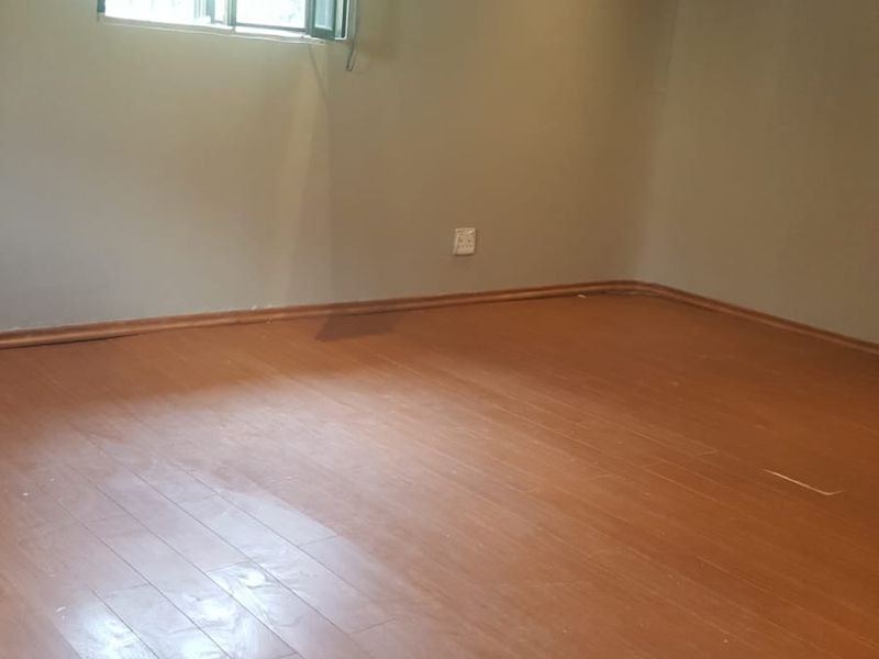 An empty bedroom featuring laminate flooring, recessed ceiling lighting, and neutral wall tones, providing a blank canvas for personalization.