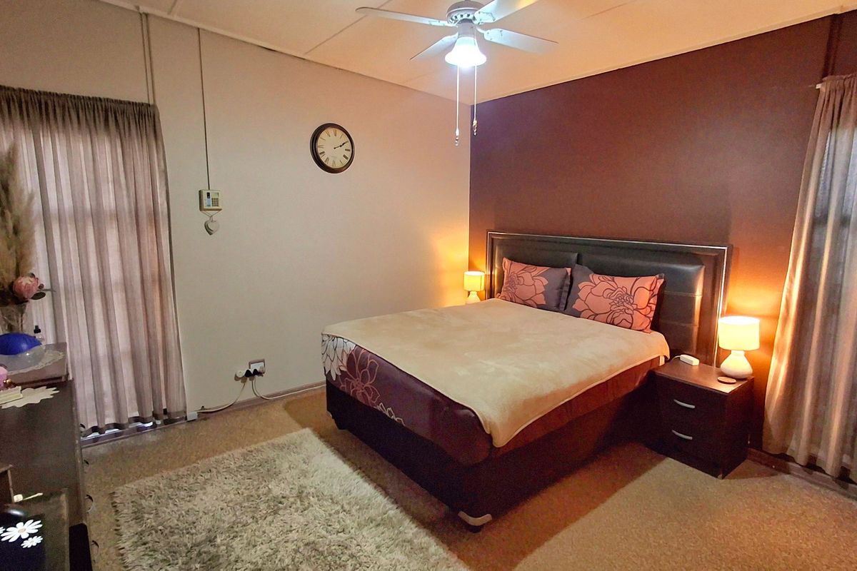 A bedroom featuring carpeted flooring, a ceiling fan, and dual windows with curtain tracks, providing a functional and comfortable sleeping space.