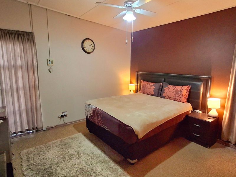 A bedroom featuring carpeted flooring, a ceiling fan, and dual windows with curtain tracks, providing a functional and comfortable sleeping space.