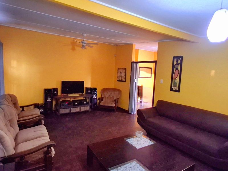 A spacious living room featuring bright yellow walls, a ceiling fan, and a sliding door leading to an adjacent room.