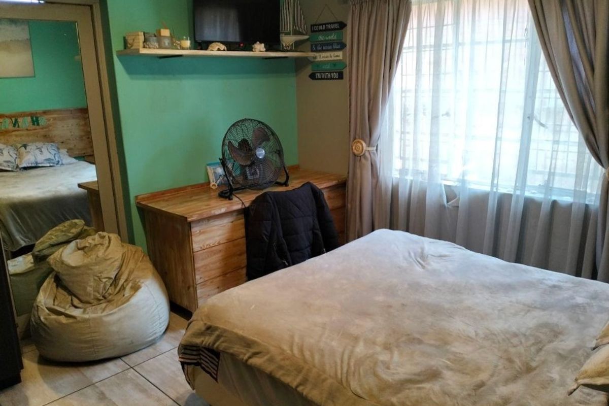 A bedroom featuring tiled flooring, built-in shelving, and a window with curtain tracks, providing a functional space with potential for modern updates.