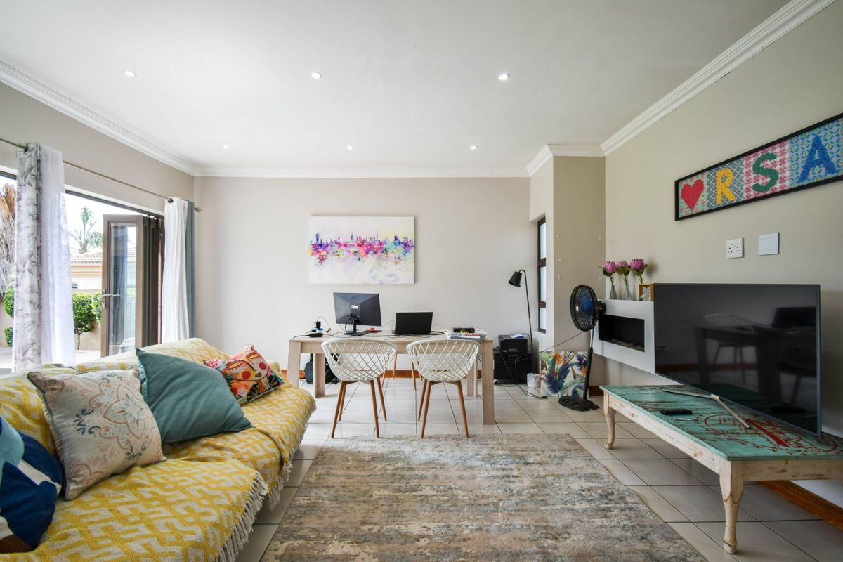 A bright and spacious living room featuring tiled flooring, recessed downlights, and a sliding glass door providing access to the outdoor area.