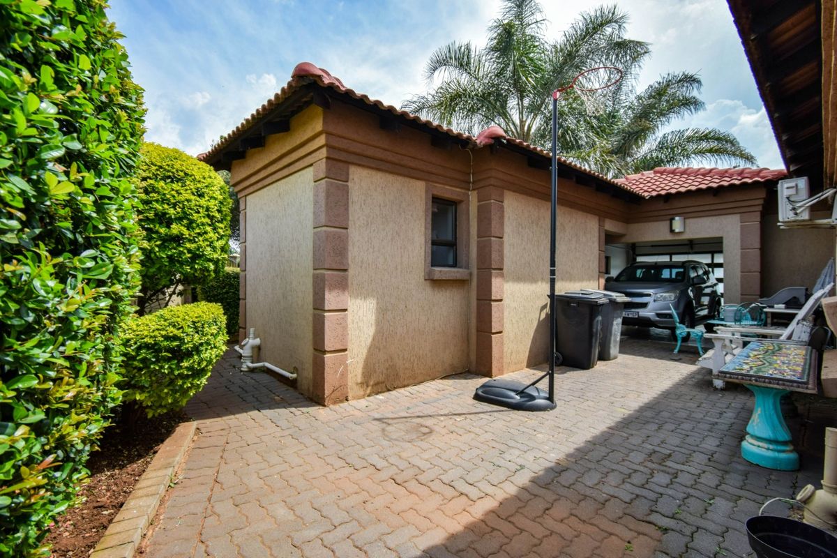 Rear exterior view of the property featuring a paved driveway, textured facade, and access to the garage area.