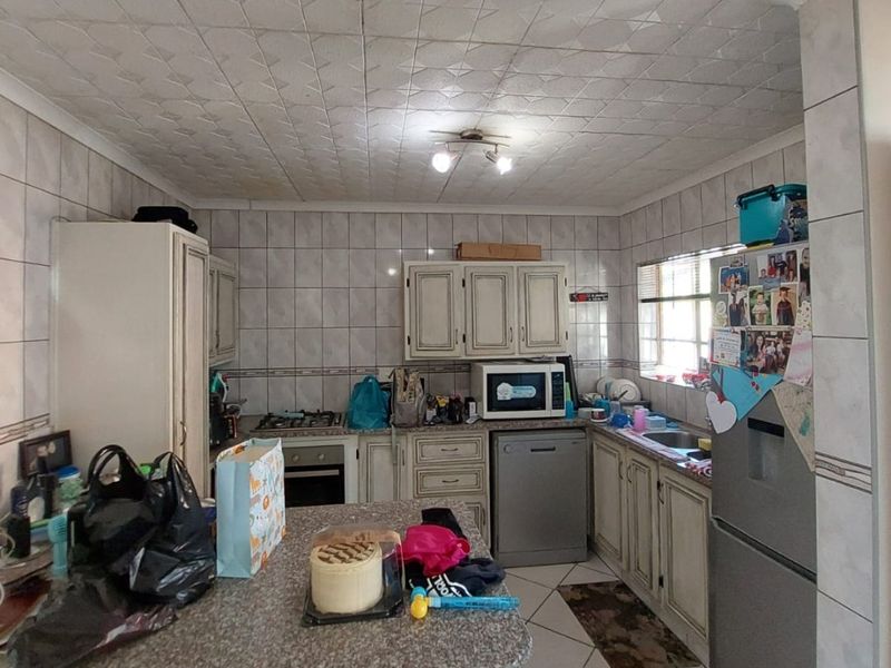 A functional kitchen featuring tiled walls and flooring, granite countertops, built-in cabinetry, and integrated appliances, offering potential for a modern renovation.