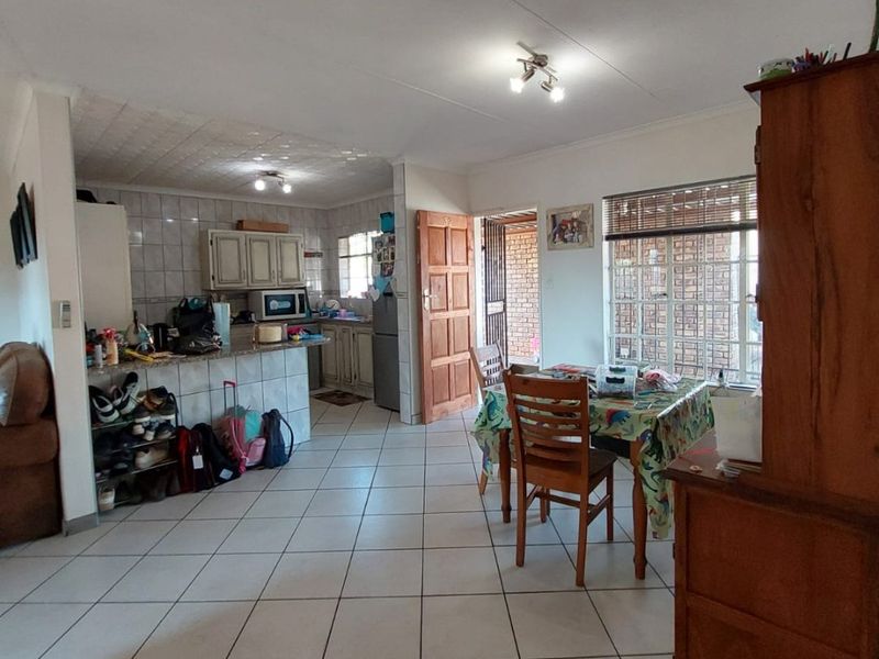 Open-plan living and kitchen area featuring tiled flooring, functional cabinetry, and direct access to an outdoor space through a security gate.