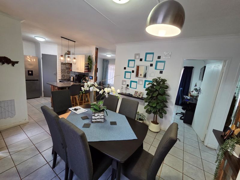 Open plan dining and kitchen area featuring tiled floors, modern pendant lighting, and a functional kitchen island with cabinetry.