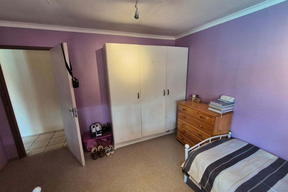 A bedroom featuring built-in wardrobe storage, carpeted flooring, and coving detail. The space would benefit from a fresh coat of paint.