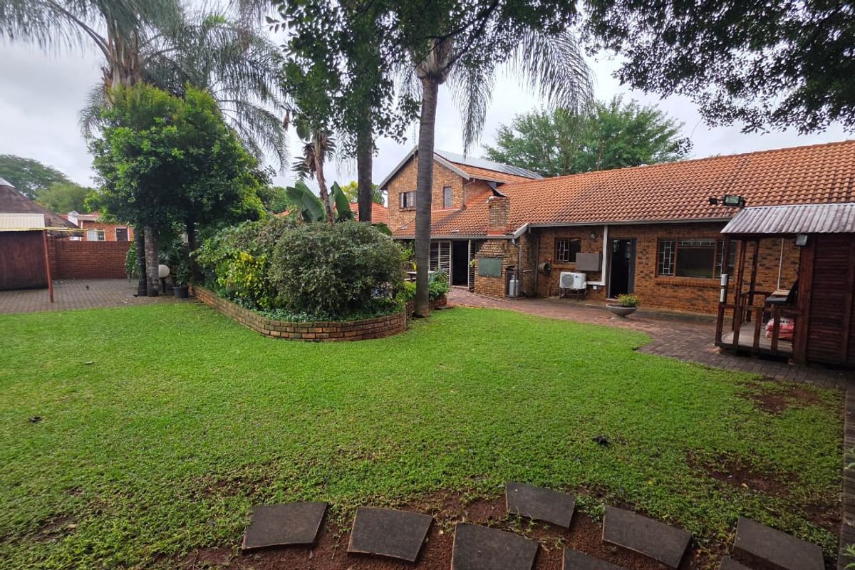 Spacious rear garden featuring a well-maintained lawn, brick-paved patio area, and established landscaping, providing a private outdoor space for relaxation.