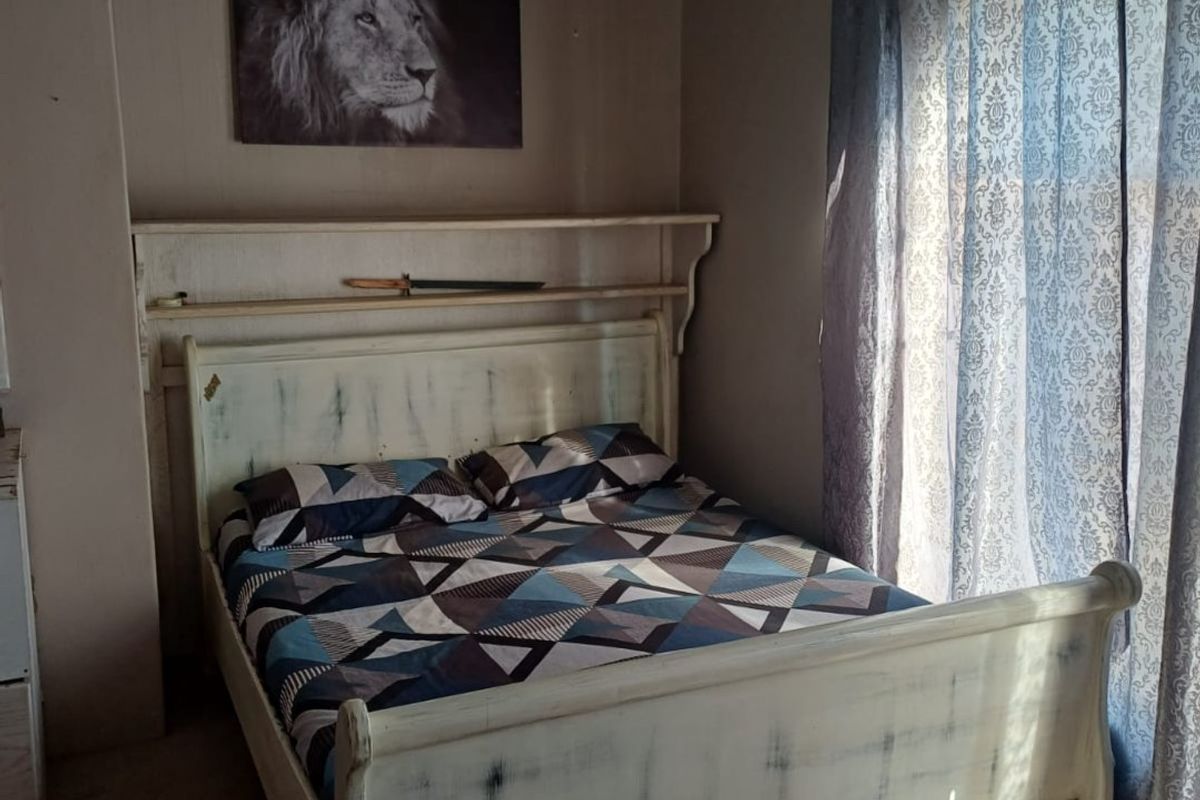 A bedroom featuring a built-in wall shelf and pendant lighting, requiring cosmetic updates to the wall finishes and flooring.