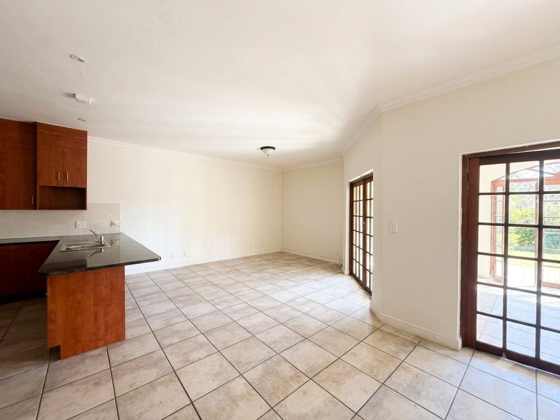 Open-plan living area featuring a kitchen with granite countertops and tiled flooring, with direct access to an outdoor patio through double french doors.