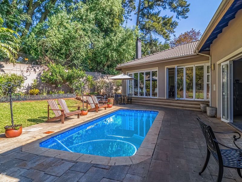 A well-maintained outdoor pool area featuring a paved patio, swimming pool, and direct access to the home through large sliding glass doors.
