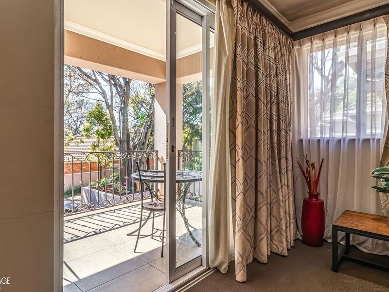 A covered balcony featuring tiled flooring and a decorative wrought iron balustrade, accessible via a sliding glass door from the interior living space.