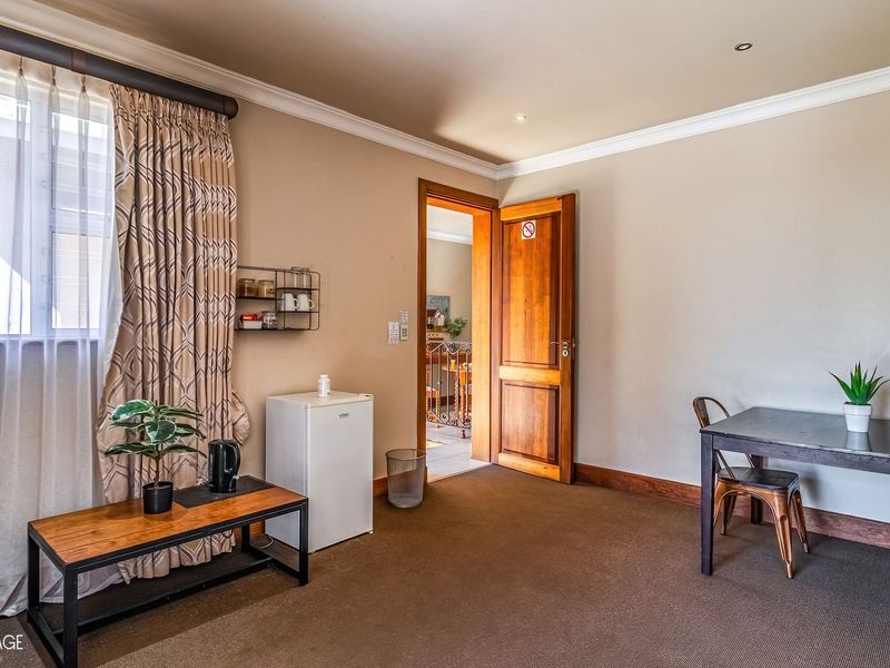 A carpeted bedroom featuring neutral walls, recessed lighting, and a wooden door leading to an adjacent space.