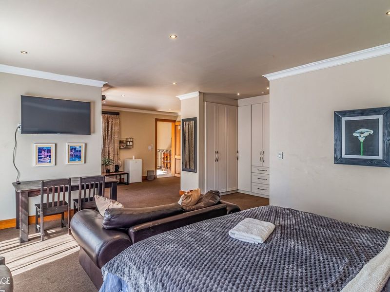 Spacious bedroom featuring neutral walls, recessed downlighting, carpeted flooring, and ample built-in cupboard storage.
