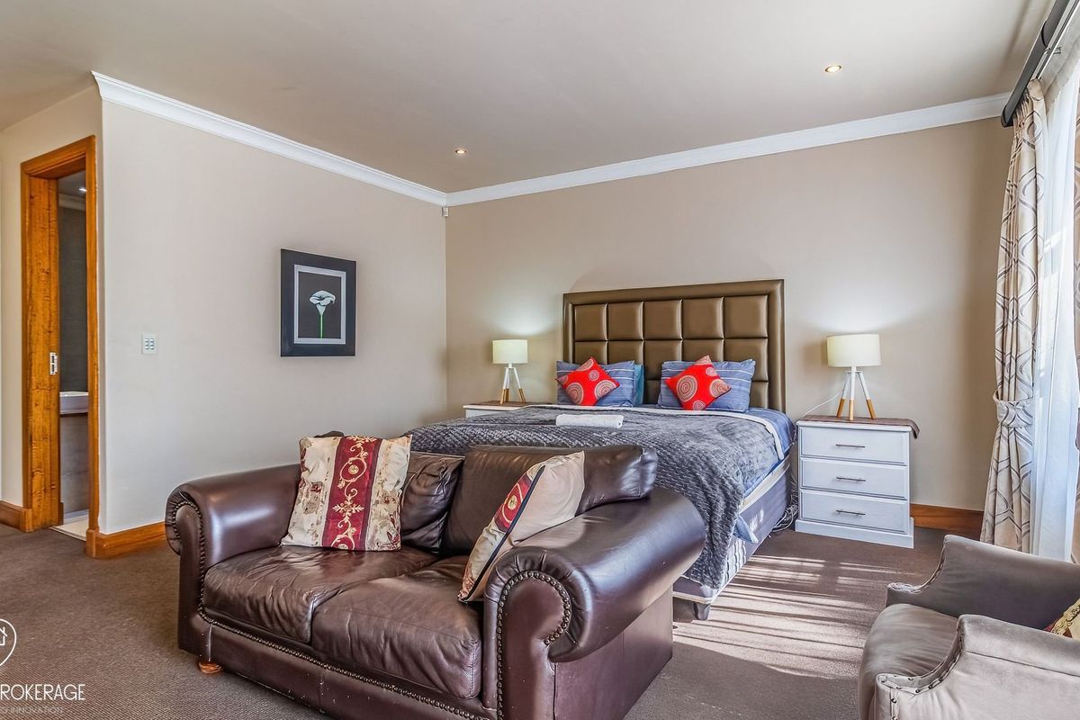 Spacious bedroom featuring neutral walls, recessed downlighting, coving, and built-in storage cupboards with direct access to an en-suite bathroom.