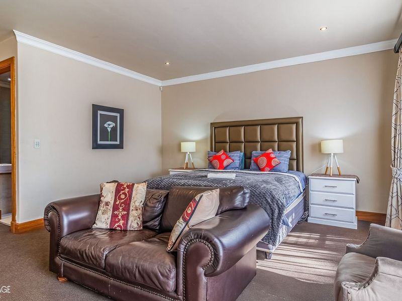 Spacious bedroom featuring neutral walls, recessed downlighting, coving, and built-in storage cupboards with direct access to an en-suite bathroom.