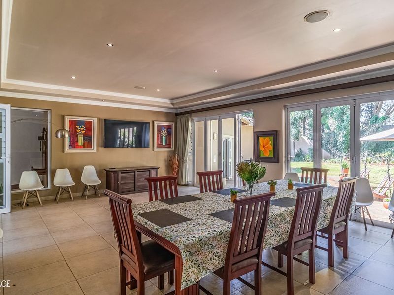 Spacious open-plan living and dining area featuring large aluminium stacking doors that provide seamless access to the garden and abundant natural light.