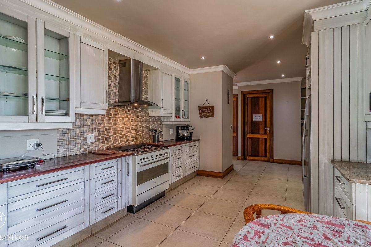 A well-appointed kitchen featuring white cabinetry, a mosaic tile backsplash, stainless steel gas stove, and tiled flooring with recessed lighting.