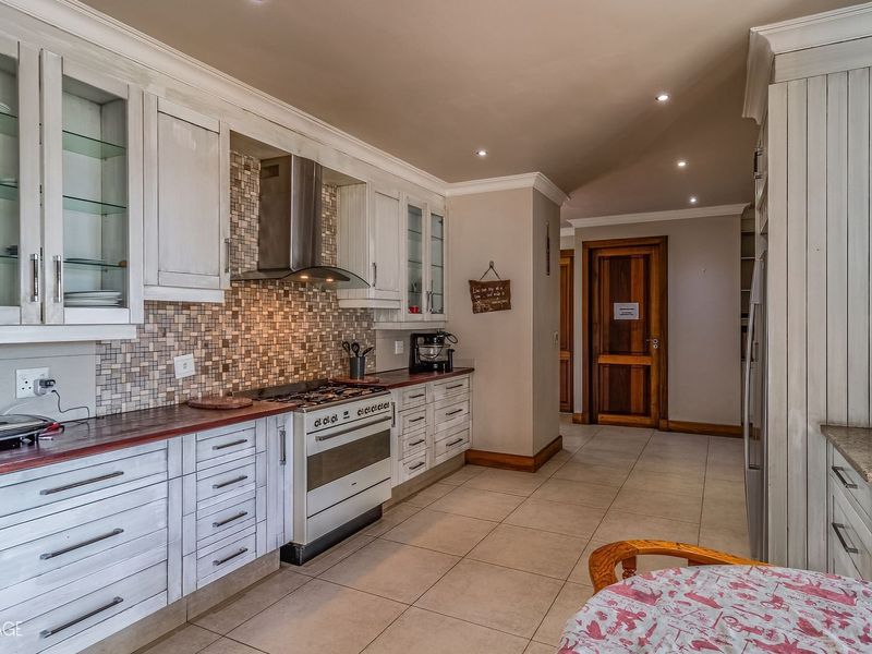 A well-appointed kitchen featuring white cabinetry, a mosaic tile backsplash, stainless steel gas stove, and tiled flooring with recessed lighting.