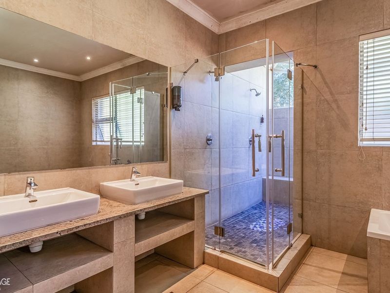 Modern bathroom featuring a double vanity with stone countertop, a spacious glass-enclosed shower, and a built-in bathtub with neutral tiled finishes.