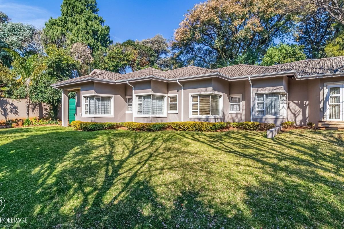 A well-maintained rear elevation of a single-story house featuring bay windows, sliding glass doors, and a spacious, manicured lawn.