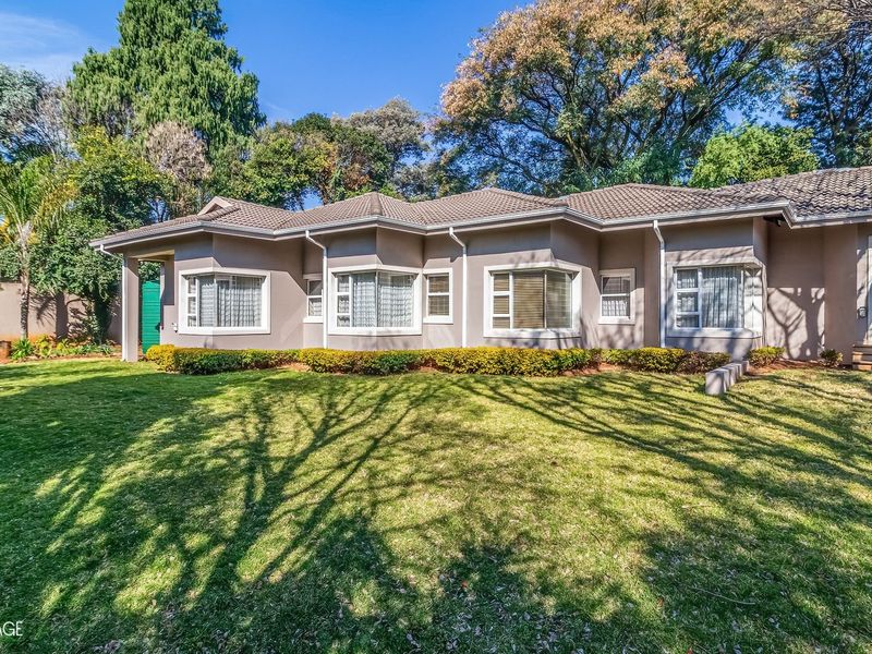 A well-maintained rear elevation of a single-story house featuring bay windows, sliding glass doors, and a spacious, manicured lawn.