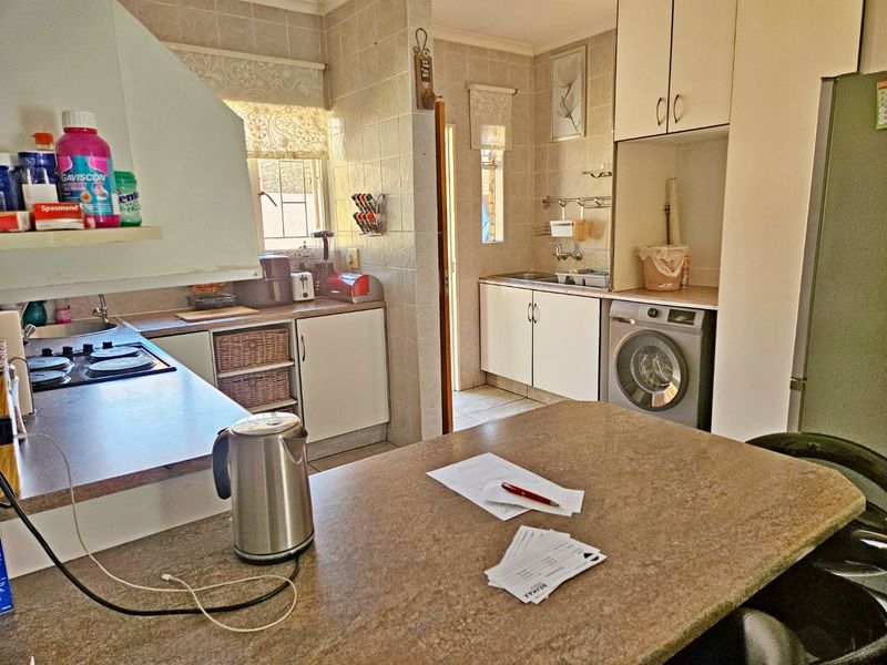 Functional kitchen featuring tiled walls, built-in cabinetry, laminate countertops, a built-in hob, and integrated laundry plumbing.