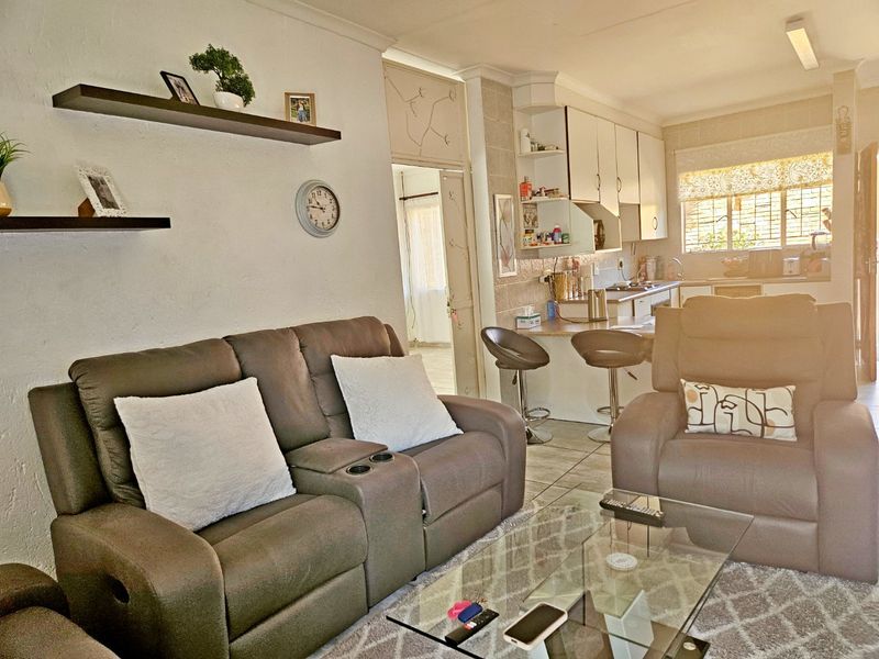 Open-plan living area featuring tiled flooring and a functional kitchen with built-in cabinetry and a breakfast bar, creating a cohesive living space.