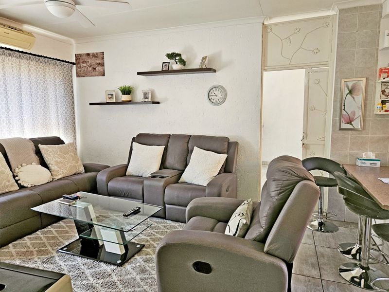 Open-plan living area featuring tiled flooring, a ceiling fan, and wall-mounted air conditioning, providing a functional and comfortable space.