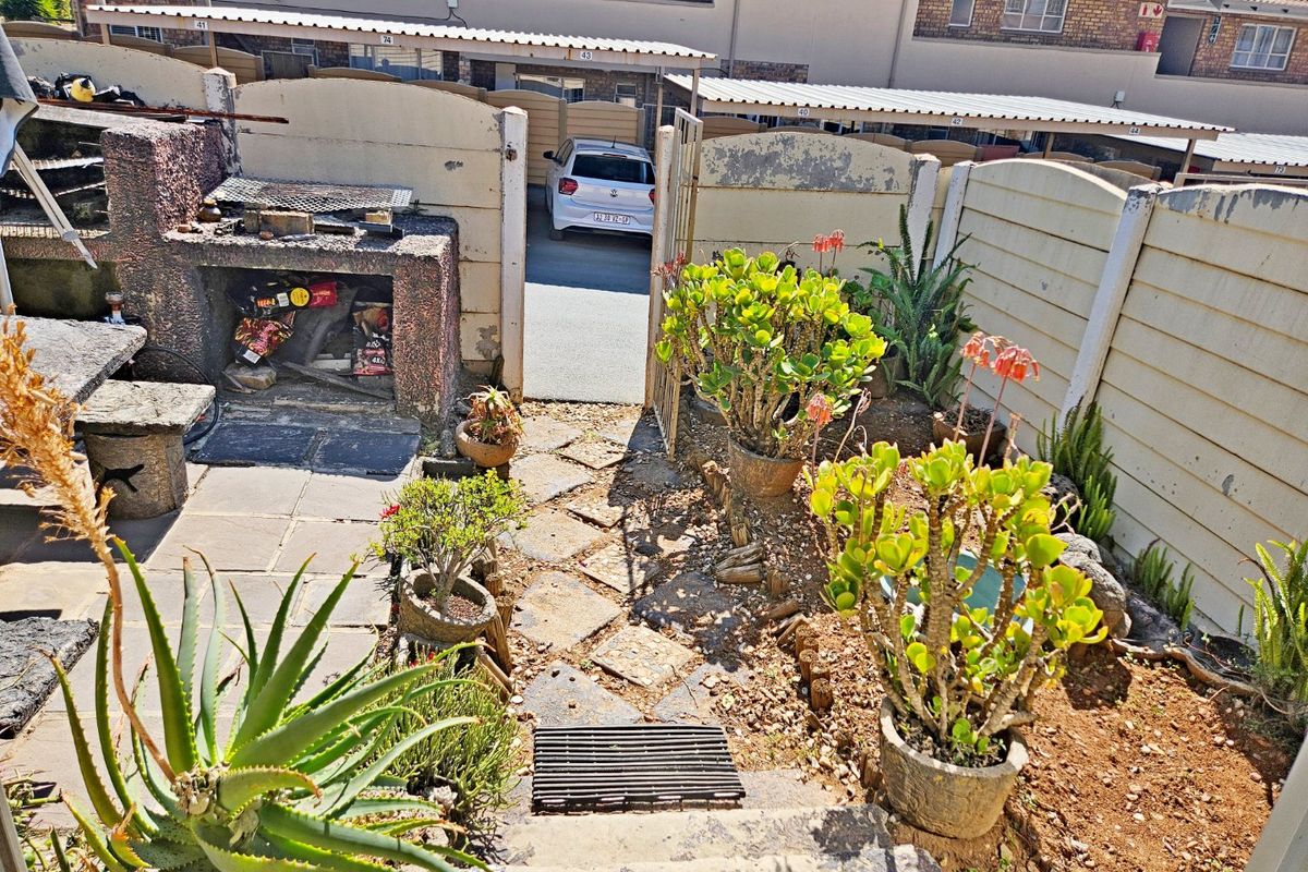 Rear courtyard area featuring a built-in braai, paved patio space, and precast boundary walling, offering potential for outdoor entertainment area improvement.