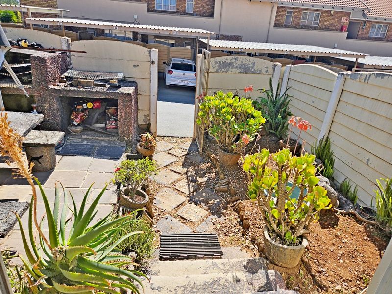 Rear courtyard area featuring a built-in braai, paved patio space, and precast boundary walling, offering potential for outdoor entertainment area improvement.