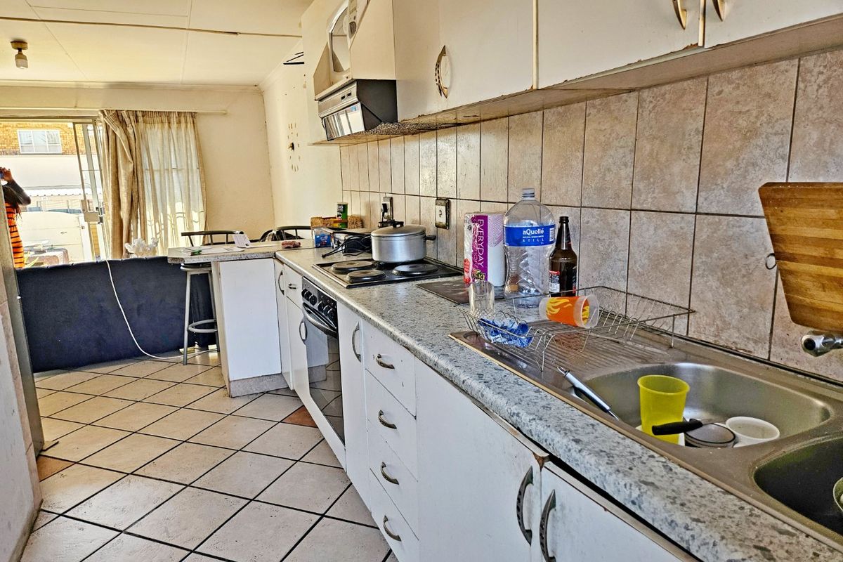 A dated kitchen featuring laminate countertops, built-in cabinetry, and an electric hob, requiring cosmetic updates to modernize the space.