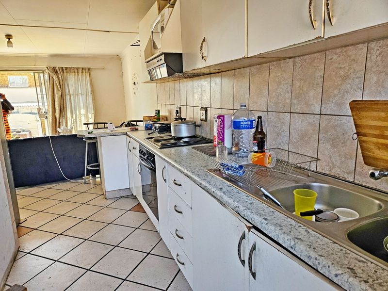 A dated kitchen featuring laminate countertops, built-in cabinetry, and an electric hob, requiring cosmetic updates to modernize the space.
