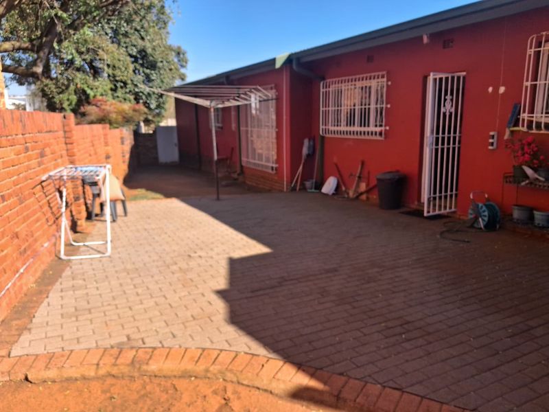 A paved rear courtyard area featuring a brick boundary wall and security-fitted windows and doors, providing a functional outdoor space.