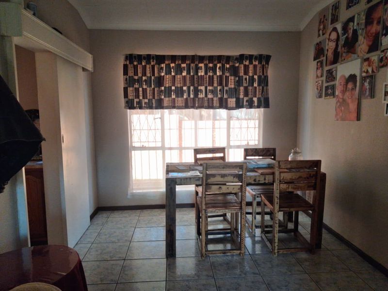 A dining room featuring tiled flooring and a window with security bars, providing a functional space for meals.
