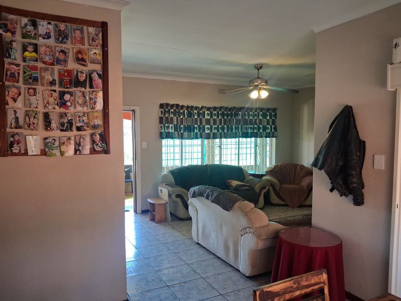 A living room area featuring tiled flooring, a ceiling fan, and security bars on the windows, providing a functional and lived-in space.