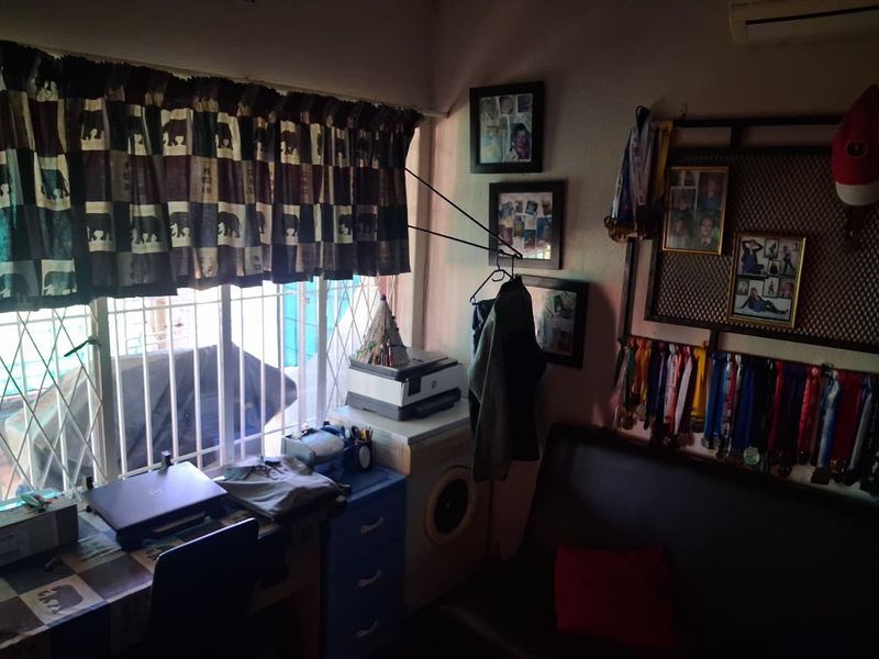 A multi-purpose utility space featuring a window with security bars and an integrated air conditioning unit.