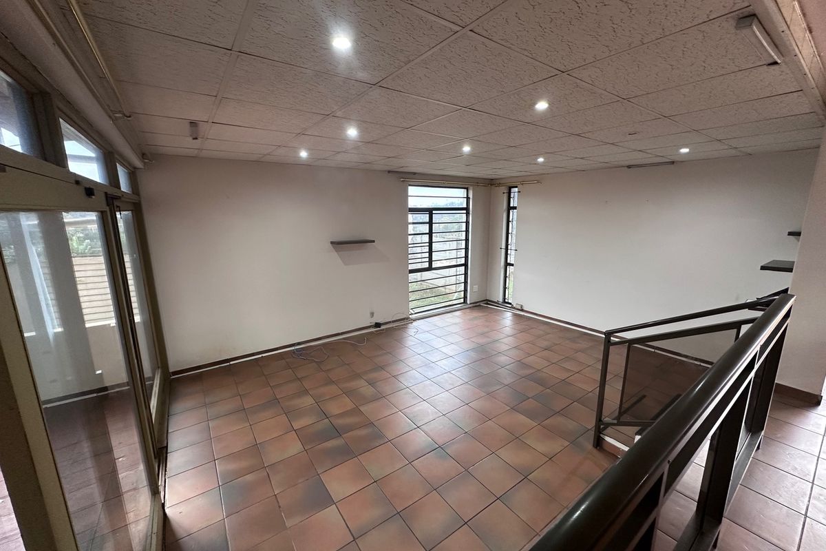 Spacious, empty living area featuring tiled flooring, a suspended ceiling with recessed lighting, and access to a balcony through sliding glass doors.