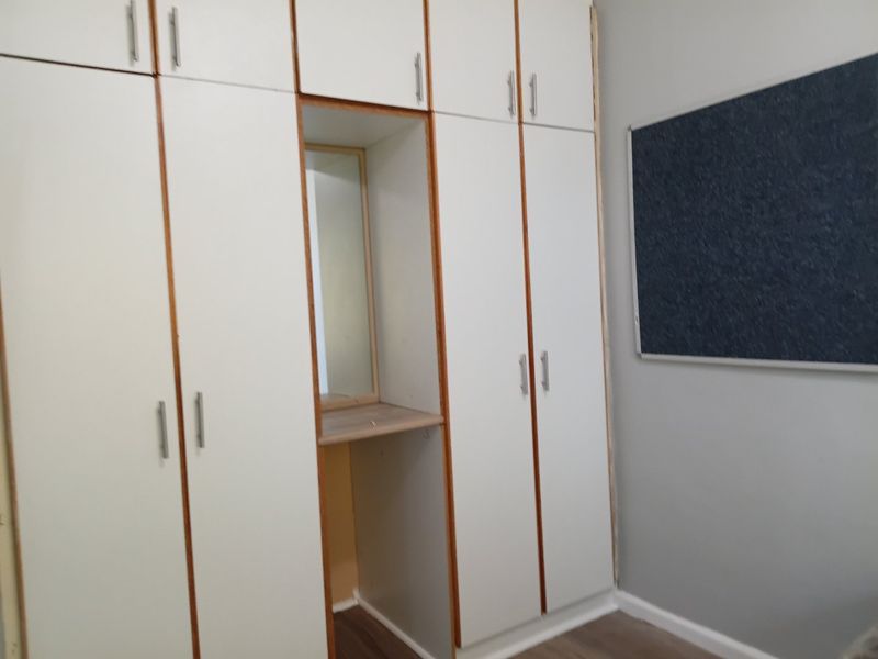 Bedroom featuring floor-to-ceiling built-in cupboards with a central vanity nook and integrated mirror.