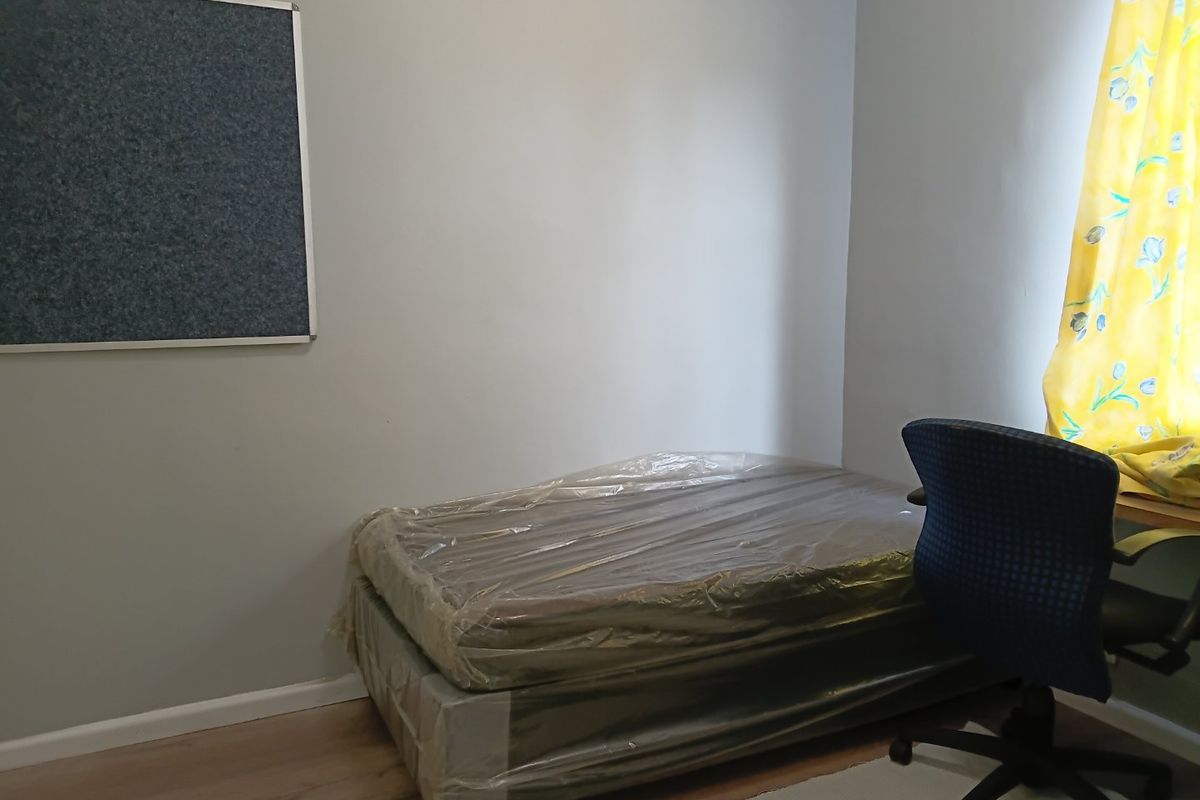 A simple bedroom featuring laminate flooring and neutral wall finishes, offering a functional space ready for personalization.
