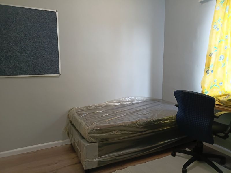 A simple bedroom featuring laminate flooring and neutral wall finishes, offering a functional space ready for personalization.