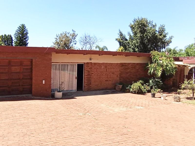 Front exterior view of a single-story brick house featuring a paved driveway, integrated garage, and sliding door entrance.