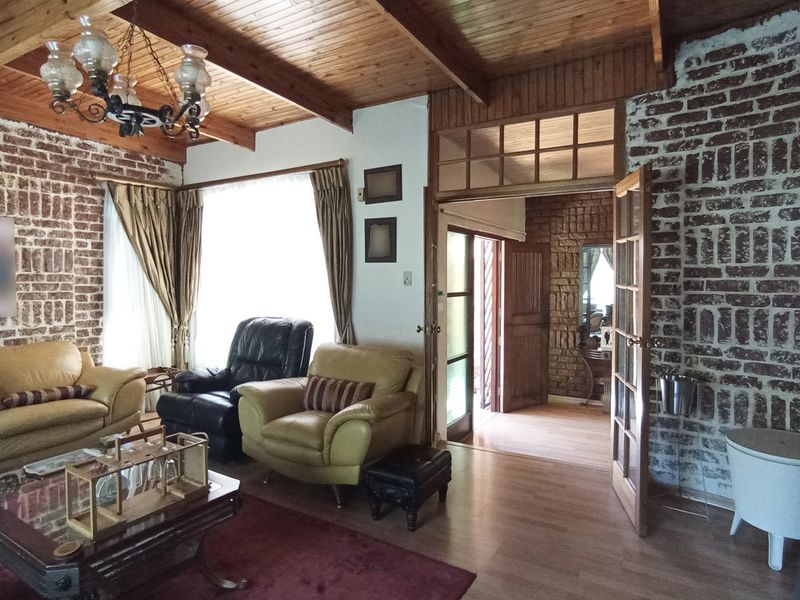 A rustic living room featuring exposed brick walls, timber beam ceilings, and warm wood-toned flooring, creating a cozy and traditional atmosphere.