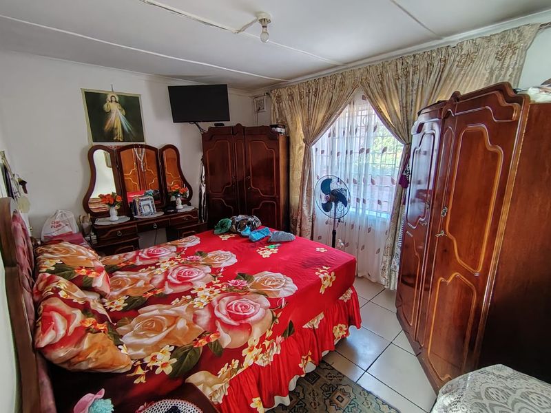 A bedroom featuring tiled flooring and a window with security bars. The room requires cosmetic updates to the ceiling and finishes.